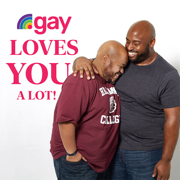 Two men hugging and the words '.gay loves you a lot!'