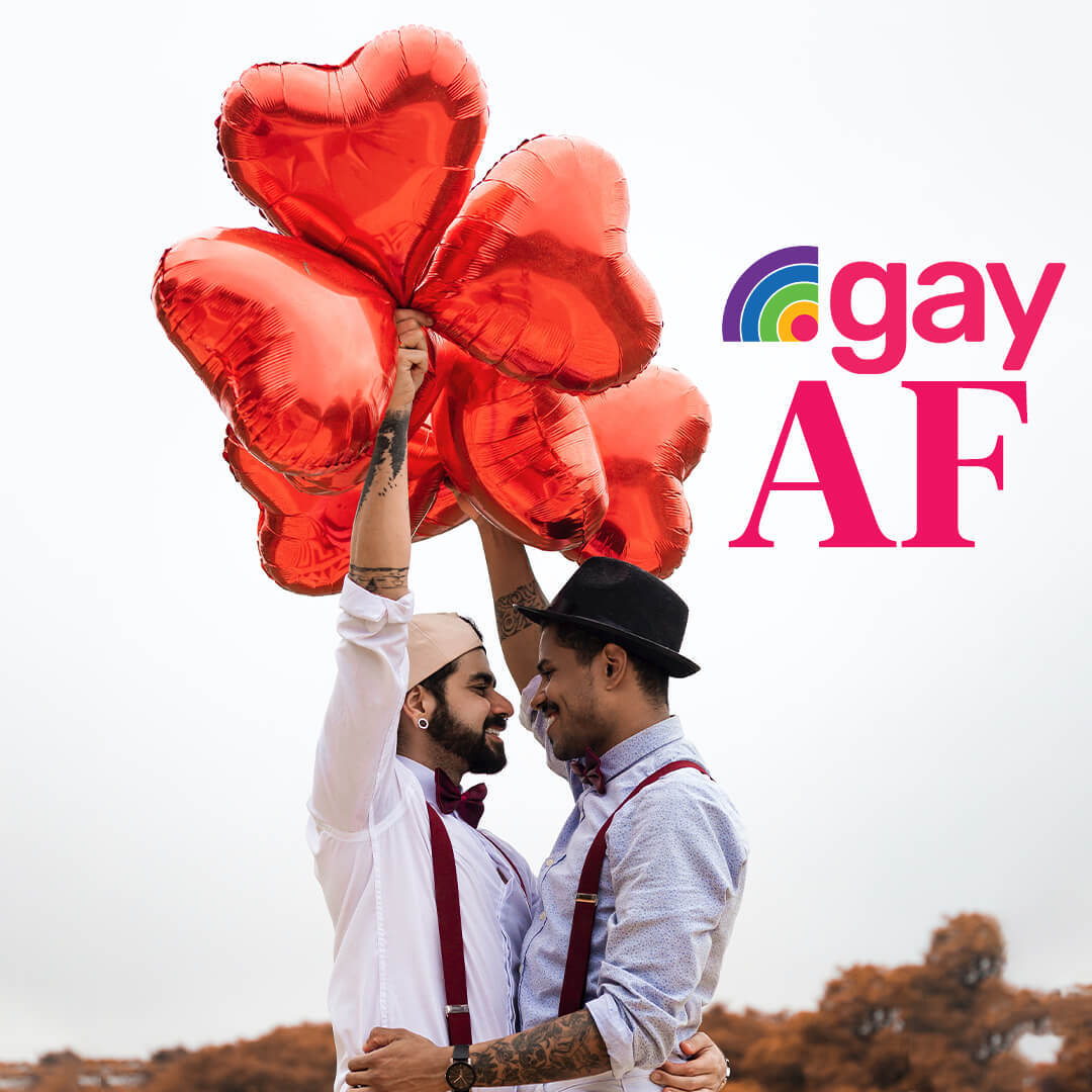Two men holding hands with heart shaped baloons and the words '.gay AF'